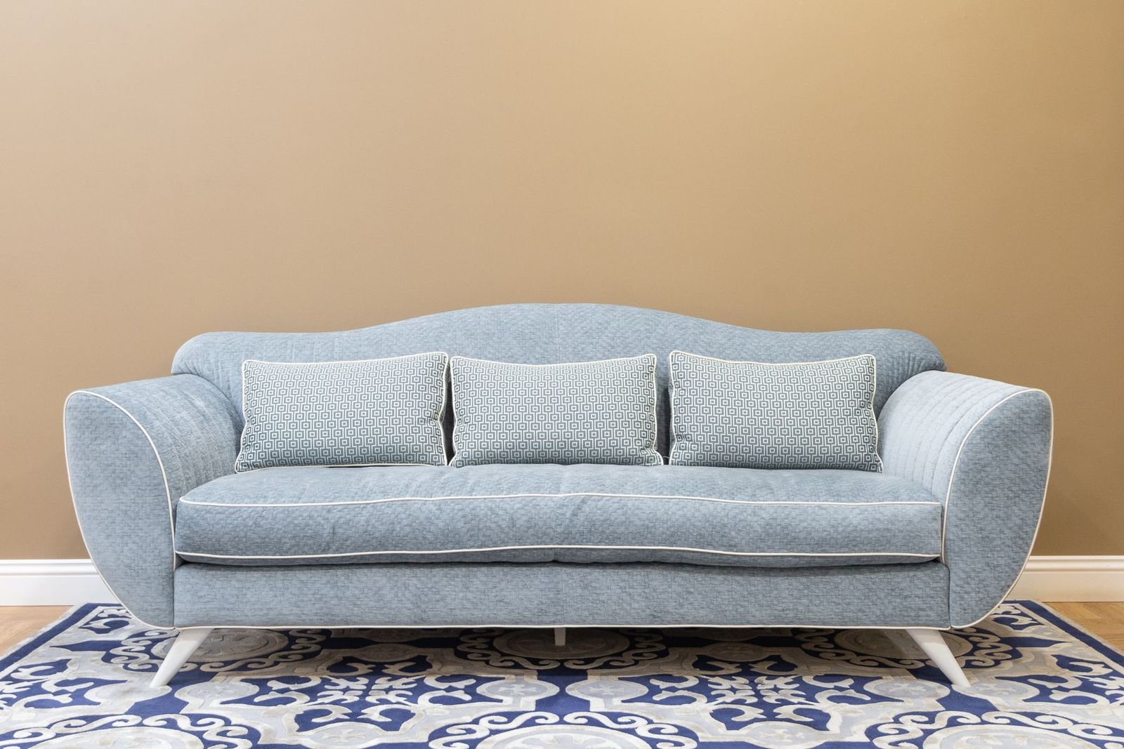 Blaues Sofa mit Kissen auf einem gemusterten Teppich